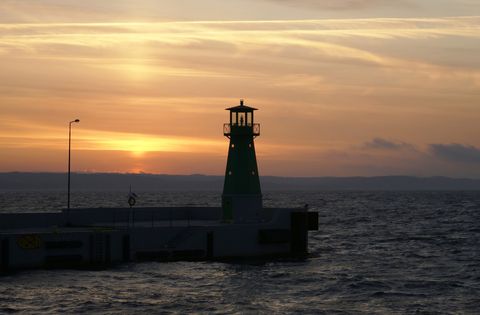 Wunderschöner Sonnenuntergang am Meer mit einem Leuchtturm im Vordergrund. Aktivferien mit Eurotrek.