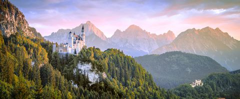 Das Schloss Neuschwanstein thront in einem wunderschönen Bergpanorama in Mitten von Wäldern. 