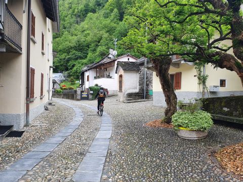 Eine Velofahrerin fährt durch das Dorf Maggia im Tessin. 
