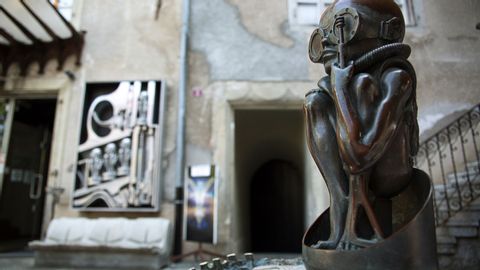 A metal statue stands at the entrance to the Gruyères Giger Museum.