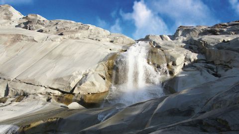 Ein Wasserfall stürzt einer Felswand hinunter an der Rhonequelle.