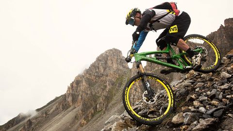Brave mountain biker in full gear on a rocky downhill.