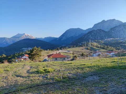 Drei Häuser vor einer Berglandschaft und grünen Flächen im Vordergrund 