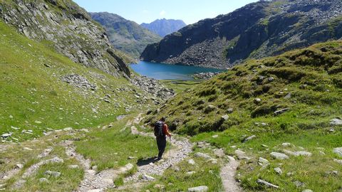 Ein Wanderer auf den Wanderwegen in Richtung Bergsee mit wunderschöner Berglandschaft.