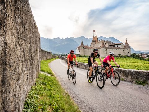Three cyclists ride past a castle in Aigle on the Eurotrek cycle tour.