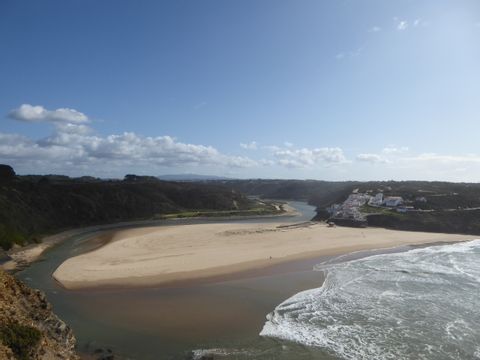Eine kleine Sandbank trennt ein Fluss vom Meer auf der Rota Vicentina in Portugal.
