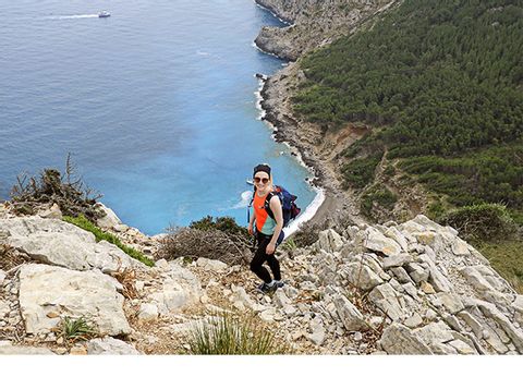 Eine Wanderin auf der Mallorca Finca Wanderung steht oben an der Bucht Coll Baix.
