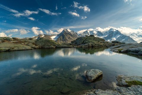 Lac de montagne clair comme du cristal avec vue sur les sommets enneigés dans un fantastique jeu de nuages.