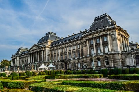 Der königliche Palast in Brüssel mit seinen3 Kuppen. Vorne der Garten und über dem Plast ein blauer beinahe Wolkenloser Himmel. 