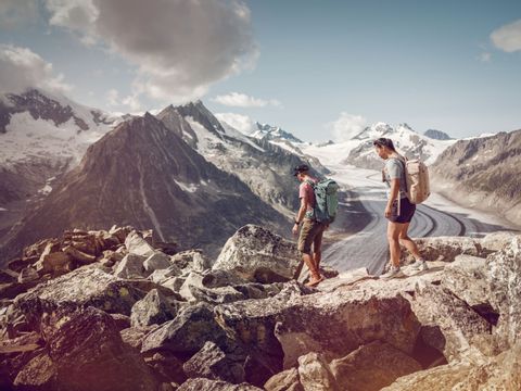 Un couple se trouve sur le sentier panoramique d'Aletsch, juste devant le glacier d'Aletsch.