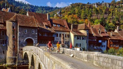 Deux cyclistes traversent un pont à St-Ursanne, dans le canton du Jura, lors de leur randonnée à vélo Eurotrek de Bâle à Nyon.