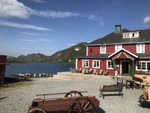Ein typisches rotes norwegisches Haus steht am Ufer vom Bygdin See. 