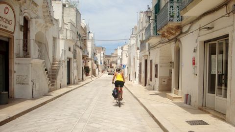 Radfahrerin in einer stark bebauten Strasse in einer Stadt in Apullien