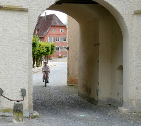 Ein Velofahrer fährt durch ein Tor in St-Ursanne. 