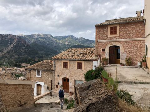 Drei Terracotta farbene Fincas auf Mallorca. Im Hintergrund die Berge und ein bewölkter Himmel
