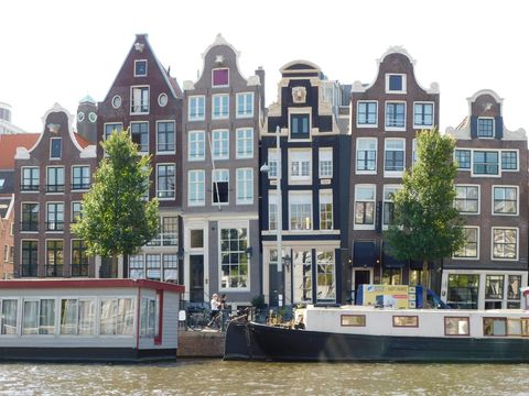 Häuserfront in Amsterdam mit Kanal und Hausbooten.
