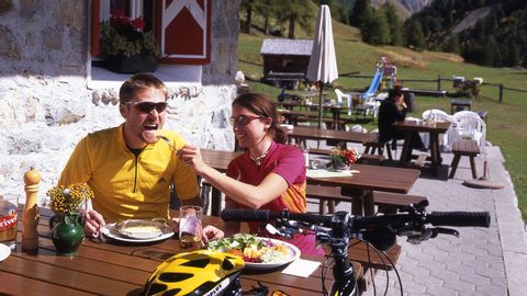 Couple de vététistes déjeunant sur une terrasse ensoleillée dans le Val Trupchun, dans le canton des Grisons.