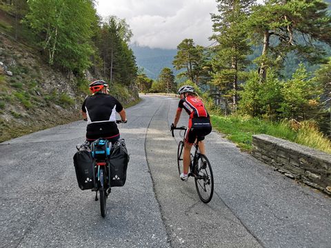 Zwei Bikerinnen fahren nebeneinander gemütlich plaudernd die Strasse zum Simplonpass hinauf. Rennvelo Oberwallis. Veloferien mit Eurotrek.