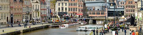 Viele Menschen tummeln sich am Flussufer im Stadtzentrum von Gent in Belgien.