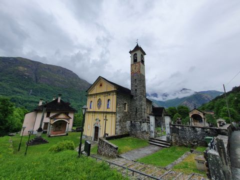 Die Kirche im Dorf von Aurigeno steht auf einer grünen Wiese. 