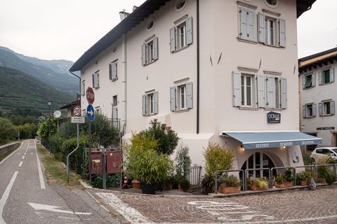 Weisses Mehrfamilienhaus zwischen Bozen und Venedig. Im Erdgeschoss ist die Gelateria/ Bistro Zenzero was auf einer hellblauen Sonnenstore geschrieben steht. 