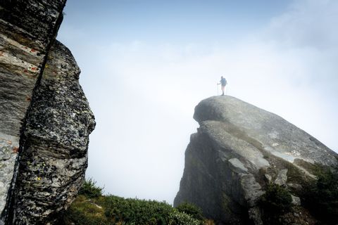 Un randonneur se tient tout seul au sommet d'un rocher.