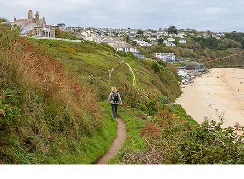 Eine Wanderin wandert an der Carbis Bay in Cornwall.