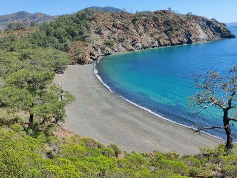 Blick auf einen Steinstrand und türkis farbenem Meer 