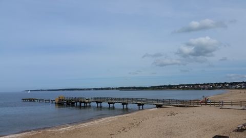 Ein langer Holzsteg ragt ins Wasser am Strand in Ängelholm in Schweden.