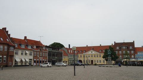 Dorfplatz mit traditionellen dänischen Häusern und Dorfbrunnen