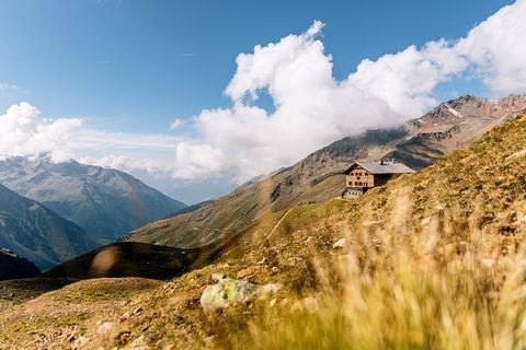 Die Sesvenna-Hütte und im Vordergrund eine Alpwiese im Gebirge. 