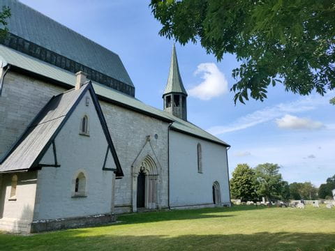 Eine weisse Kirche steht auf einem Feld in Lau auf Gotland. 