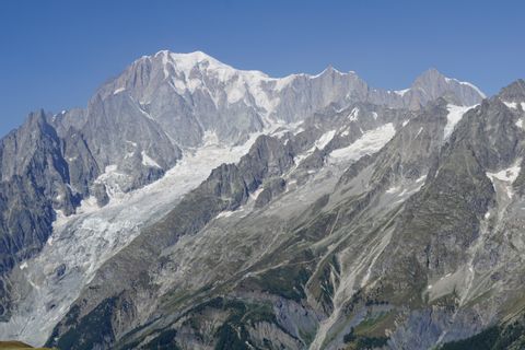 Ein Berg, teilweise mit Schnee bedeckt, unter strahlend blauem Sommerhimmel.