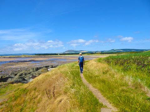 Wanderer bestaunt die malerische Landschaft am Fife Coastal Path