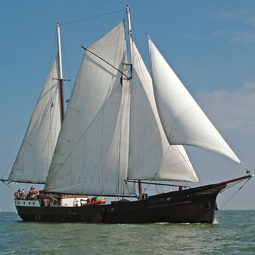 Traditionelles zweimastiges Segelschiff Wapen fan Fryslan mit weißen Segeln auf ruhigem blauen Wasser unter teilweise bewölktem Himmel.