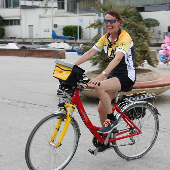 Radfahrerin mit einem Fahrrad von Eurobike auf einem öffentlichen Platz in der Toskana.