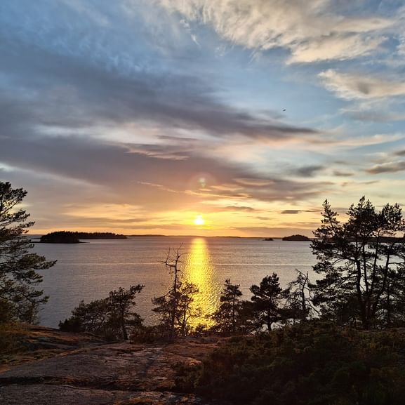 Sonnenuntergang in Mossala, Finnland. Blick von einem Aussichtspunkt über das Meer umgeben von Bäumen.