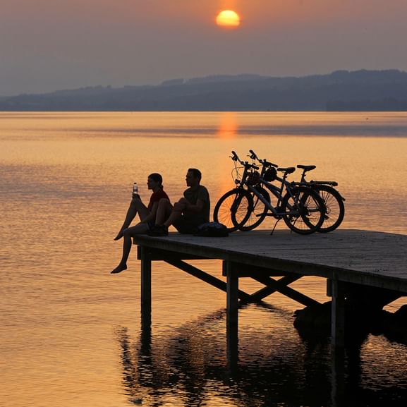 Zwei Biker, sitzen mit ihren Rädern, bei einem wunderschönen Sonnenuntergang, am Steg.