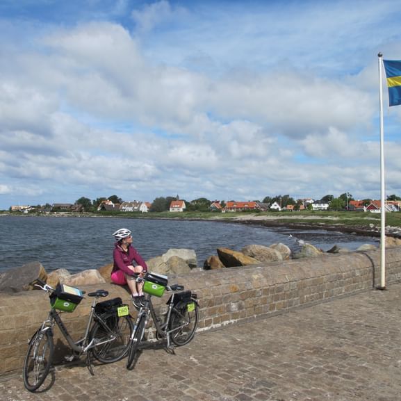Eine Frau macht Pause an einem Steg auf ihrer Velotour entlang der Westküste Schwedens.