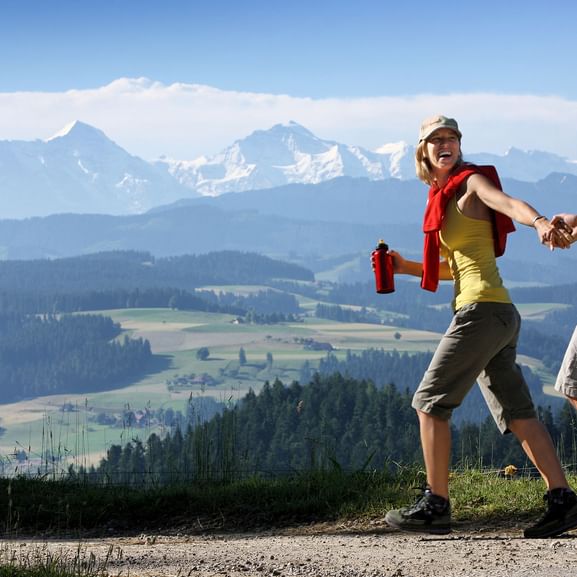 Ein Paar wandert in Moosegg im Kanton Bern auf dem Trans Swiss Trail mit Bergen im Hintergrund.