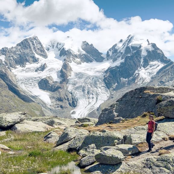Ein Wanderer-Pärchen läuft über ein Steinplateu. Im Hintergrund ,die Gletscherzungen die kurvig vom Berg hinunter führen.