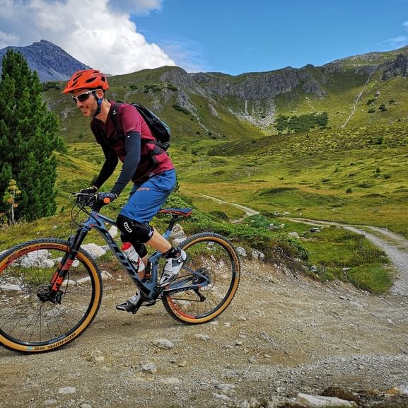 Ein Mountainbiker fährt auf einem Feldweg im Schweizer Nationalpark.