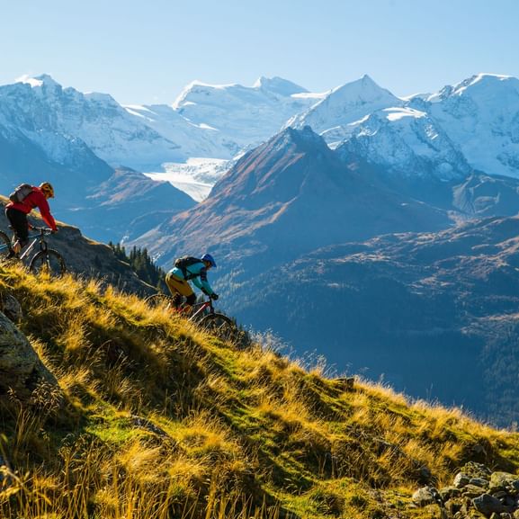 Zwei Mountainbiker fahren im Wallis einen Berg hinunter.