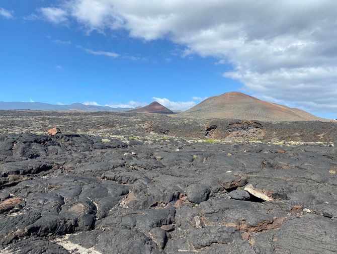 Auf Lavafeldern auf El Hierro sieht man im Hintergrund den Vulkan. 