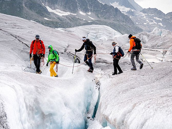 Touristen überqueren den Aletschgletscher mit einem Bergführer.
