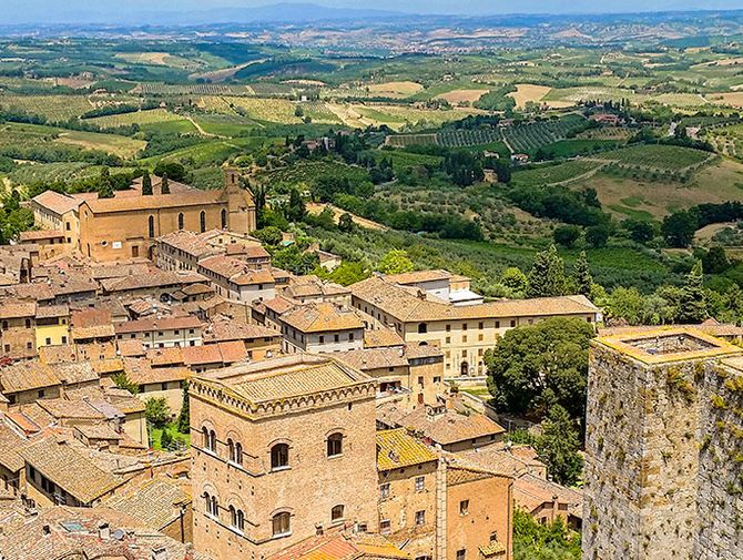 Von einem Turm in San Gimignano in der Toskana in Italien sieht man auf die umliegenden Weinreben und die Altstadt. 