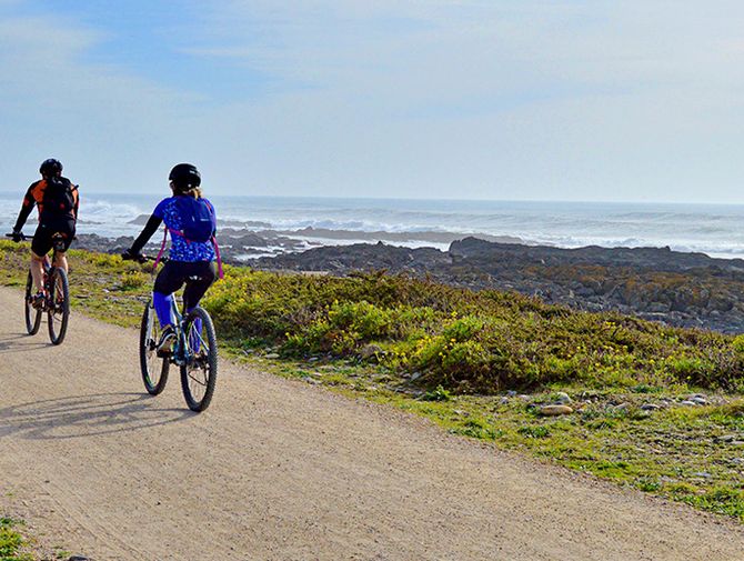 Radfahrer an der Küste im Hintergrund das Meer. 