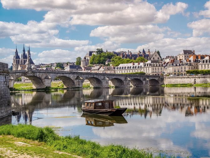 Man sieht auf eine Steinbrücke über die Loire. Auf der anderen Flussseite befindet sich das Schloss Blois. 