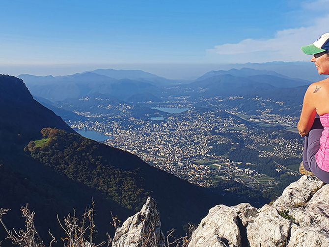 Eine Frau geniesst die Aussicht auf Lugano und Umgebung.