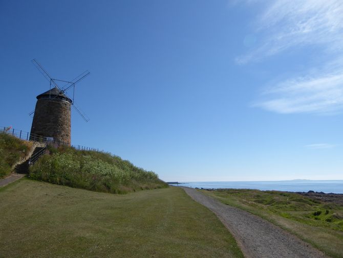 Eine alte Windmühle steht neben dem Wanderweg der Küstenwanderung in Schottland.